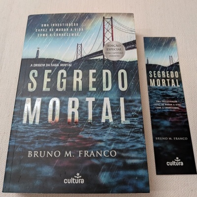 Livro 'Segredo Mortal' e marcador de livro com capa azul e imagem de uma ponte.