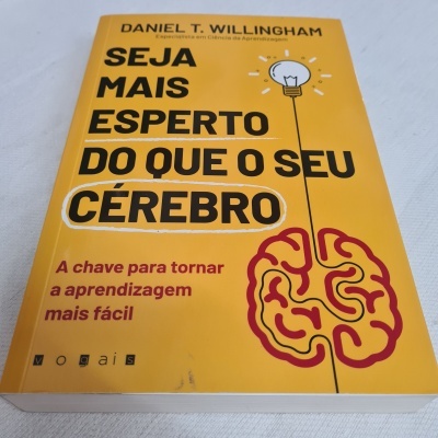Capa amarela de livro com título em preto e vinho, ilustração de cérebro e lâmpada