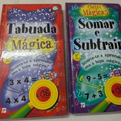 Dois livros infantis coloridos de matemática com títulos Tabuada Mágica e Somar e Subtrair em mesas brancas.
