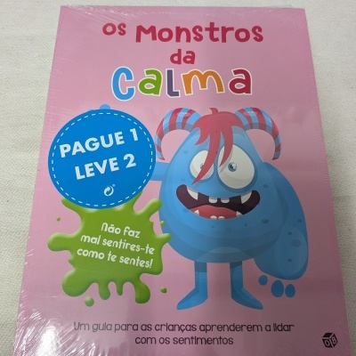 Livro com capa rosa e monstro azul com cabelos vermelhos.