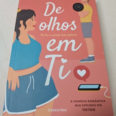 Capa de livro 'De olhos em Ti' de Amy Lea, com ilustrações de mulher e homem em fundo cor de salmão.