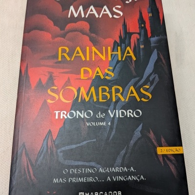 Capa do livro Rainha das Sombras com ilustração de montanhas e castelo sob céu vermelho