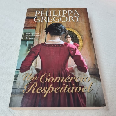Capa do livro 'Um Comércio Respeitável' de Philippa Gregory com mulher em vestido vermelho e espelho oval
