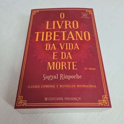 Capa de livro vermelho com texto dourado 'O Livro Tibetano da Vida e da Morte'