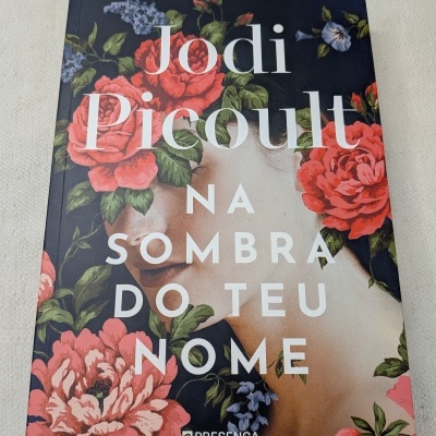 Capa de livro com flores vermelhas e rosto de mulher e texto do título.