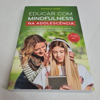 Capa de livro verde com imagem de duas raparigas, uma a ajudar a outra com auscultadores e tablet