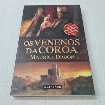 Capa do livro 'Os Venenos da Coroa' de Maurice Druon com figura de rei e castelo