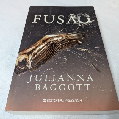 Livro 'Fusão' de Julianna Baggott com asa dourada na capa sobre fundo claro