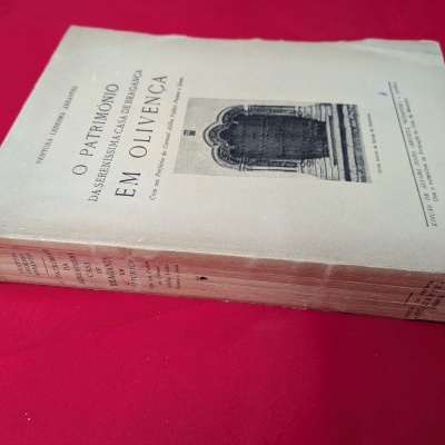 Livro antigo com capa branca sobre tecido vermelho