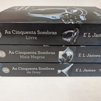 Três livros da série As Cinquenta Sombras empilhados com capas pretas