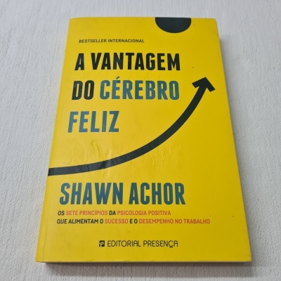 Livro amarelo 'A Vantagem do Cérebro Feliz' de Shawn Achor sobre superfície branca