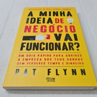 Livro amarelo com título em letras pretas e vermelhas e texto vermelho sobre uma superfície branca