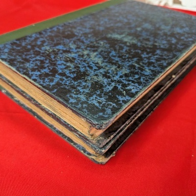 Dois cadernos antigos com capas azuis e pretas sobre fundo vermelho