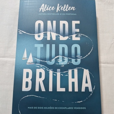 Livro azul 'Onde Tudo Brilha' de Alice Kellen com ilustração de ondas e velas.