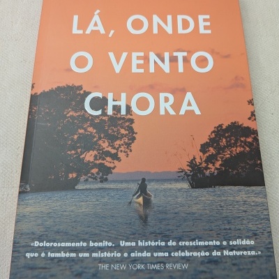Livro LÁ, ONDE O VENTO CHORA de Delia Owens com imagem de canoa num rio e árvores