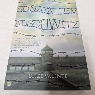 Capa de livro com o título SONATA EM AUSCHWITZ em arame farpado e nome do autor Luize Valente