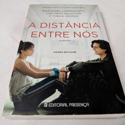 Capa do livro A distância entre nós com duas pessoas sentadas de frente uma para a outra