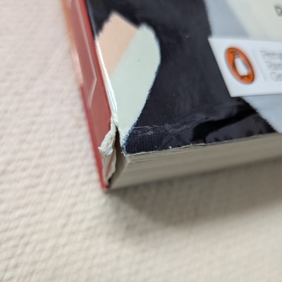 Canto de livro com capa plastificada preta e branca, lombada vermelha e texto visível na capa.