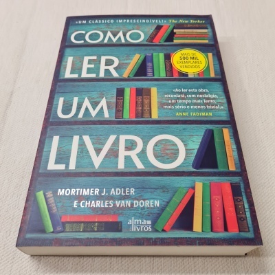 Capa do livro 'Como Ler Um Livro' com ilustrações de livros coloridos em fundo azul