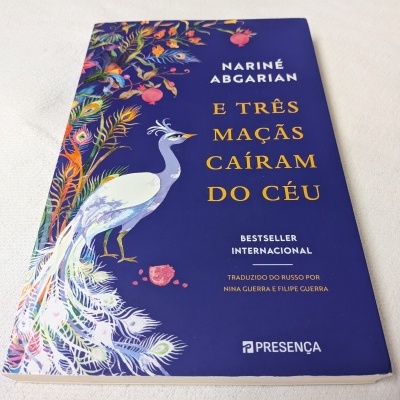 Capa de livro azul com pavão colorido e título em português
