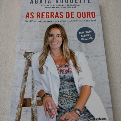 Livro a cores com foto de mulher sorridente vestindo casaco branco e vestido estampado, título AS REGRAS DE OURO.