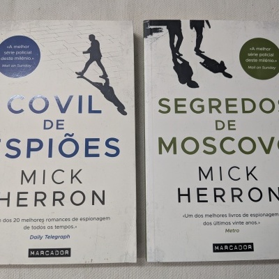 Dois livros de espionagem de Mick Herron, Covil de Espiões e Segredos de Moscovo, com citações promocionais na capa.