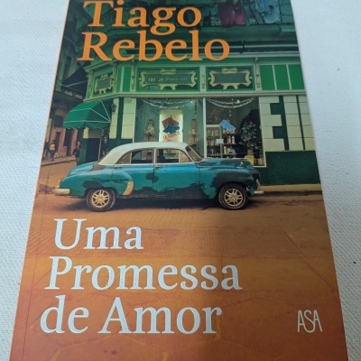 Capa de livro com carro antigo azul e branco e texto Tiago Rebelo Uma Promessa de Amor