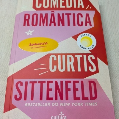 Capa de livro em tons vermelhos e rosa com grandes textos e selos.