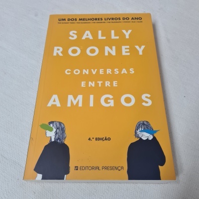Capa do livro 'Conversas entre Amigos' de Sally Rooney, fundo amarelo com ilustrações de duas pessoas e texto branco