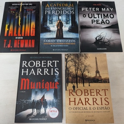 Conjunto de cinco livros em capa mole dispostos sobre superfície branca.