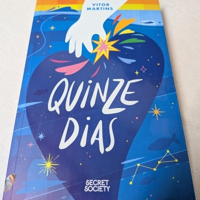Capa de livro azul com título Quinze Dias e mão segurando estrela colorida