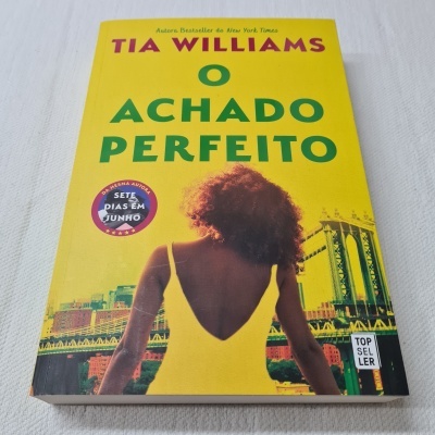 Capa de livro amarelo com mulher de vestido amarelo e ponte ao fundo