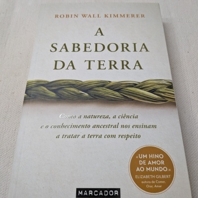 Livro A Sabedoria da Terra com capa branca e corda verde trançada