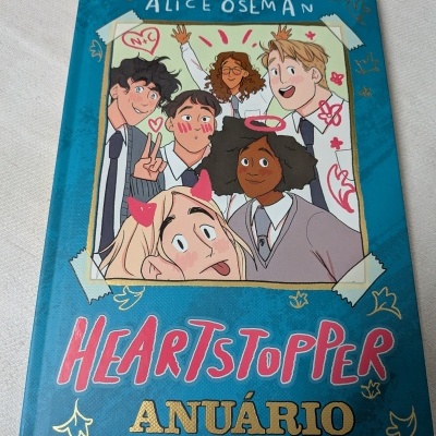 Capa de livro azul com ilustração de personagens e texto Heartstopper Anuário.