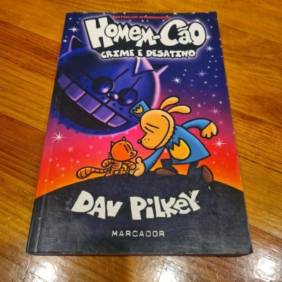 Capa do livro Homem-Cão Crime e Desatino de Dav Pilkey com ilustrações coloridas sobre piso de madeira