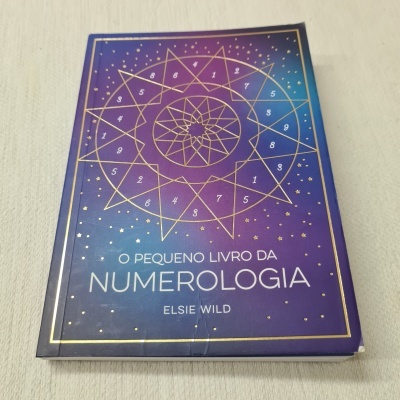 Livro O Pequeno Livro da Numerologia em tons azul e roxo com detalhes dourados