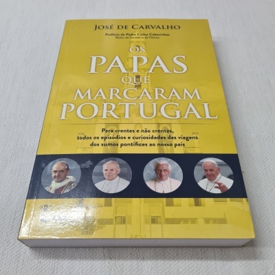 Livro amarelo 'OS PAPAS QUE MARCARAM PORTUGAL' com fotos de papas na capa