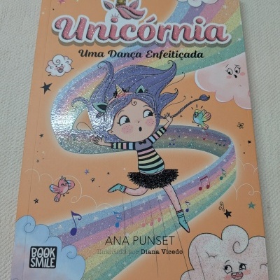 Capa de livro infantil Unicórnia Uma Dança Enfeitiçada com ilustração colorida brilhante de menina dançando em arco-íris