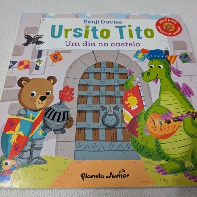 Capa de livro infantil Ursito Tito Um dia no castelo com urso cavaleiro e dragão verde a tocar alaúde