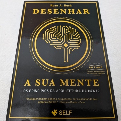 Livro preto e dourado Desenhar a sua mente com desenho de cérebro em circuitos e texto na capa