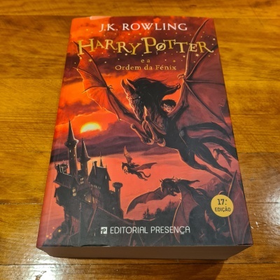 Capa do livro 'Harry Potter e a Ordem da Fénix' de J.K. Rowling com ilustração em tons vermelhos e pretos e selo '17.ª EDIÇÃO'