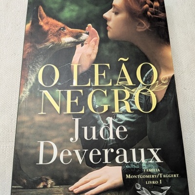 Capa do livro O Leão Negro com raposa e mulher ruiva