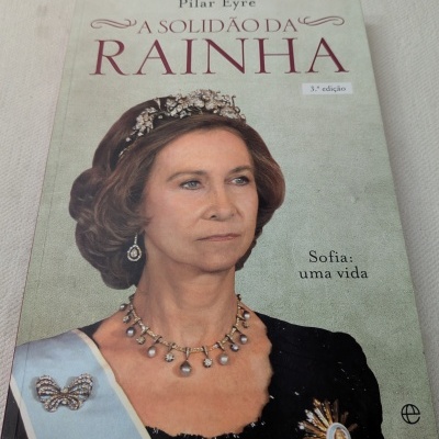 Capa do livro A Solidão da Rainha com retrato de mulher com joias e faixa azul