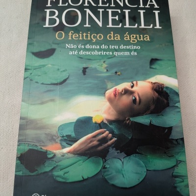 Capa do livro O feitiço da água de Florencia Bonelli com uma mulher na água e folhas de lírios.