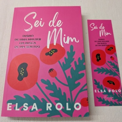 Livro e marcador de páginas cor de rosa com ilustração de papoilas vermelhas e folhas verdes e texto branco