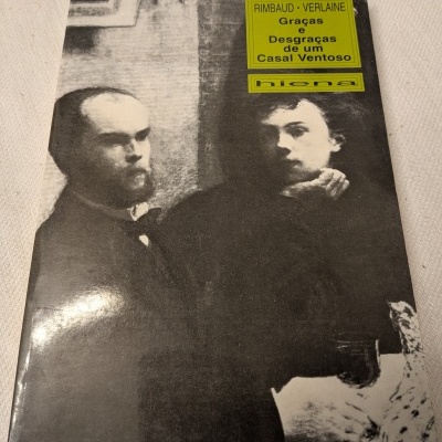 Capa de livro a preto e branco com dois homens e título em etiqueta verde no canto superior direito