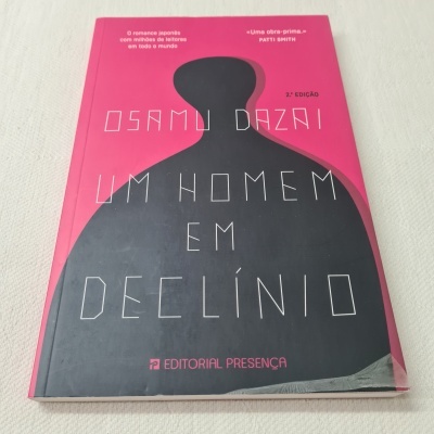 Capa do livro 'Um Homem Em Declínio' de Osamu Dazai, fundo rosa com silhueta negra