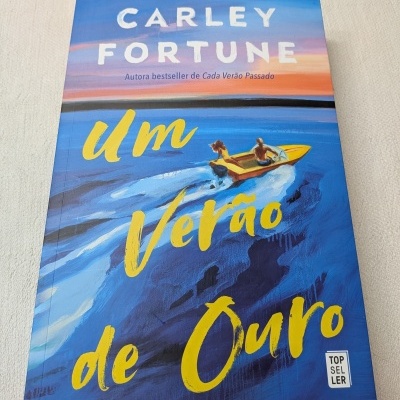 Capa do livro Um Verão de Ouro com ilustração de barco no mar e texto em amarelo e branco