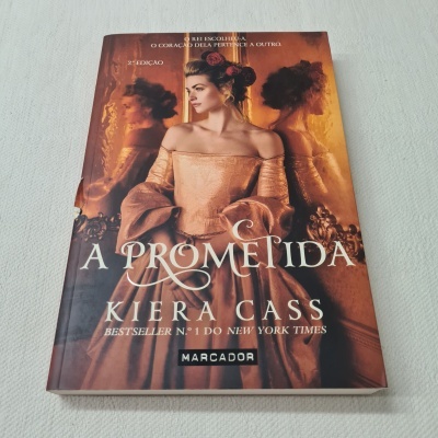 Livro 'A Prometida' de Kiera Cass com capa ilustrada por mulher em vestido de época