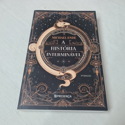 Livro 'A História Interminável' de capa preta com ilustrações douradas sobre uma superfície clara